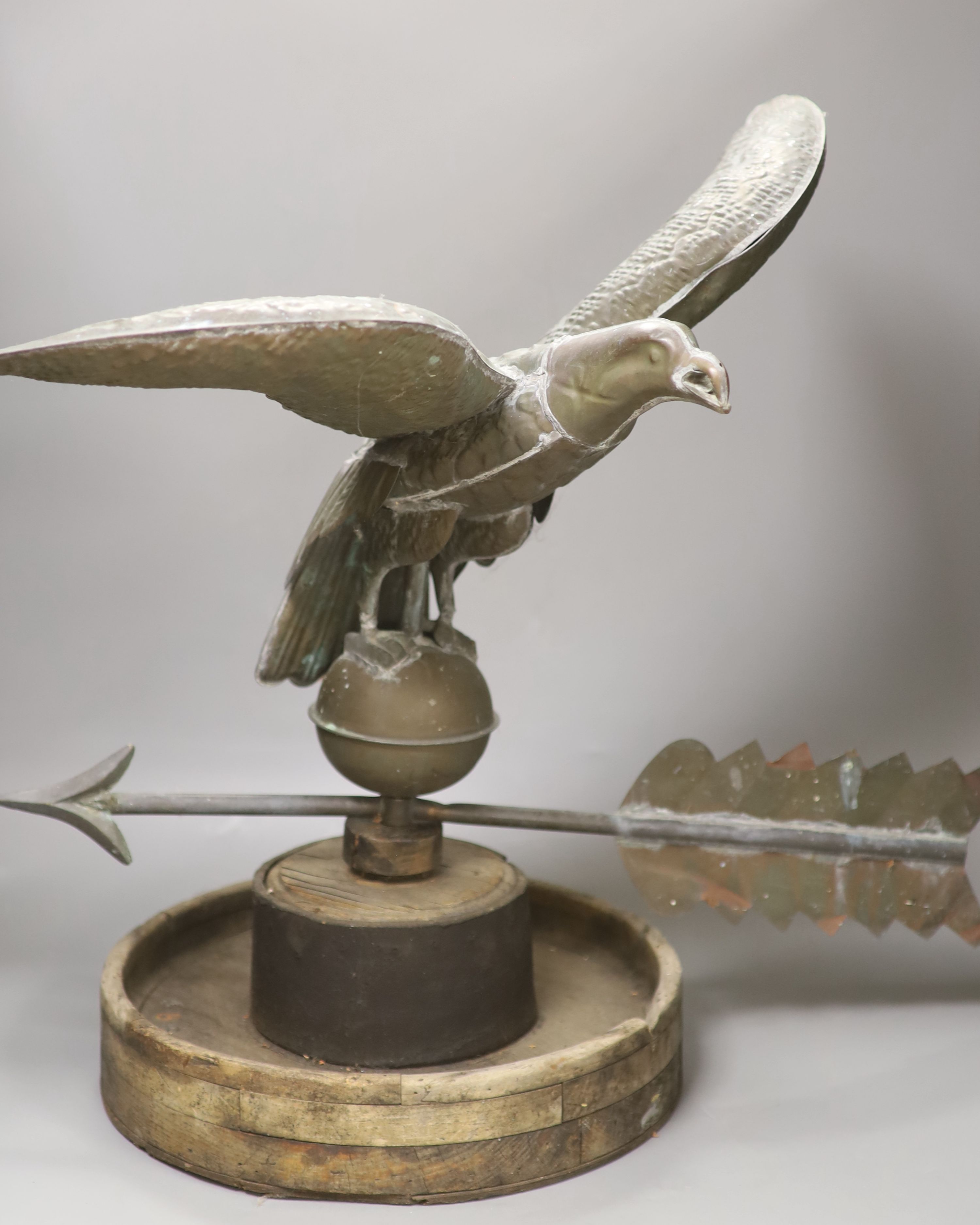 A 19th century American copper weather vane, modelled as an eagle, on an associated wooden base, width 62cm height 58cm